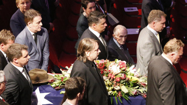 Sir John Carrick, seated right, watches as Tom Uren's coffin passes during his state funeral at the Sydney Town Hall in 2015.  The two men were POWs together in World War II.