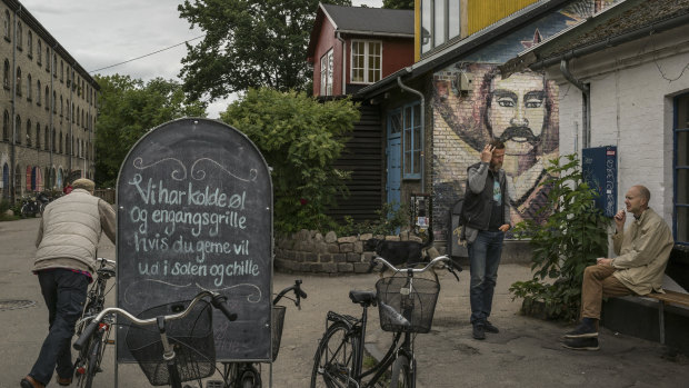 Men speak next to graffiti depicting Mexican revolutionary Emiliano Zapata, outside a bar in Christiania Freetown in the centre of Copenhagen.