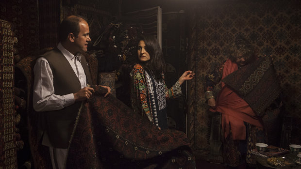 Wahid Abdullah, left, shows foreign customers rugs in his shop, Herat Carpets, on Chicken Street in Kabul, .