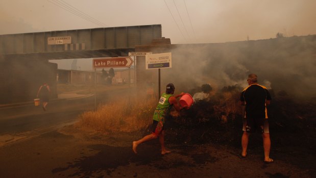 Locals douse spot fires by the side of the road in Lithgow.