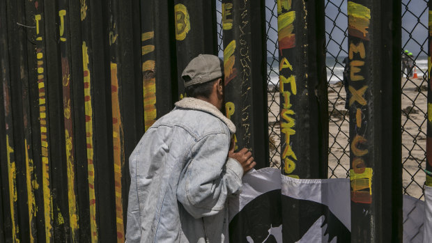 A man looks through a border fence to the US side in Tijuana, Mexico, in April.