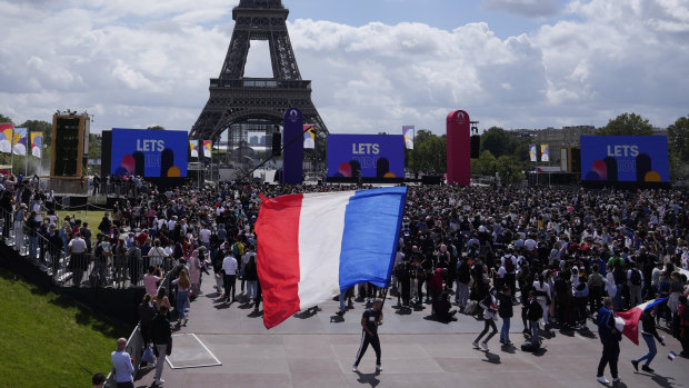 A man unfurls a French flag at the Olympics fan zone at Trocadero Gardens in front of the Eiffel Tower.