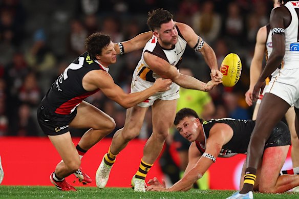 Jai Newcombe handballs whilst being tackled by Marcus Windhager.