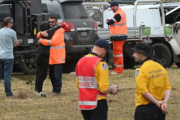 Lily’s father Jim, wearing an orange high-vis jacket, is embraced at the command post on Thursday.