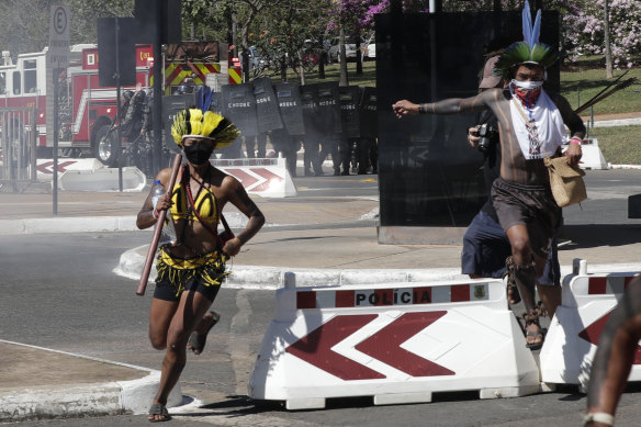 Indigenous protesters run from police outside Congress in Brasilia, Brazil, after being barred from entering.