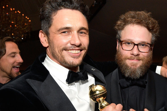 Actor James Franco holds his 2018 Golden Globe award at an after-party with actor Seth Rogen.