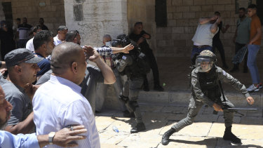 Israeli border policemen swing their batons at Muslim worshippers outside the Dome of the Rock Mosque in the Al-Aqsa Mosque compound in Jerusalem on Friday. 