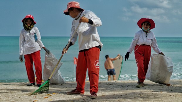 The Kuta Beach cleaners use rakes and gloves to collect the waste that washes onto the beach's white sand shore.