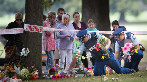 Police gather flowers left for the victims and hang them on the fence of the mosque on Tuesday. 