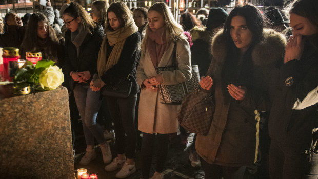 People place candles and flowers at the Brueder Grimm monument after a vigil for the victims near the Midnight shisha bar.