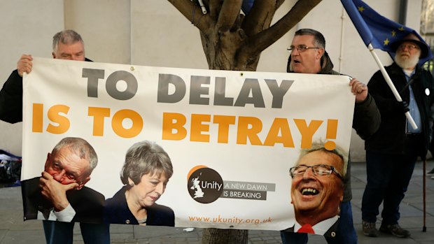 An anti-Brexit remain in the European Union supporter, right, stands next to pro-Brexit supported holding a banner outside the Houses of Parliament in London.