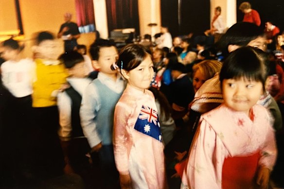 The writer, centre, in primary school, wearing an Ao Dai, or traditional Vietnamese dress with an Australian flag.