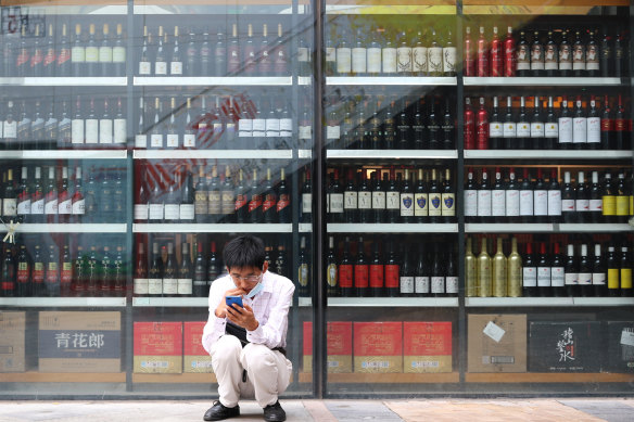 A man sits in front of a wine shop that sells Australian wines in eastern Beijing’s Tongzhou district. 