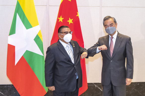 China’s Foreign Minister Wang Yi at right bumps elbows with with Myanmar’s Foreign Minister U Wunna Maung Lwin in Chongqing, China on June 8, 2021. Beijing abstained from the UN vote condemning the junta. 