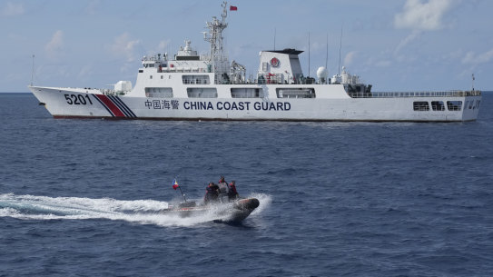 The crew of Philippine Coast Guard patrol vessel BRP Malabrigo rides a motor boat past China Coast Guard ship.