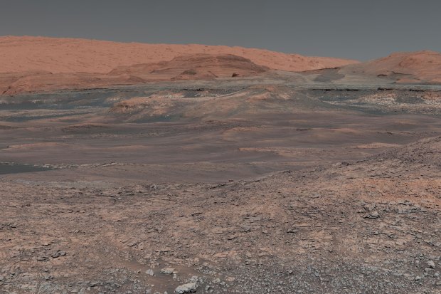 Welcome to Mars, where Mount Sharp rises in the distance. In the middle ground are clay-bearing rocks that scientists hope will help ascertain the role of water on the planet.