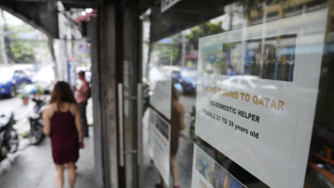 A woman walks beside a sign about hiring domestic helpers for the Middle East outside an office in Manila. 