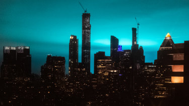 Buildings stand as the night sky is illuminated by blue light in New York.