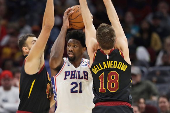 Philadelphia's Joel Embiid (centre) is squeezed between Cavs duo Ante Zizic (left) and Matthew Dellavedova.