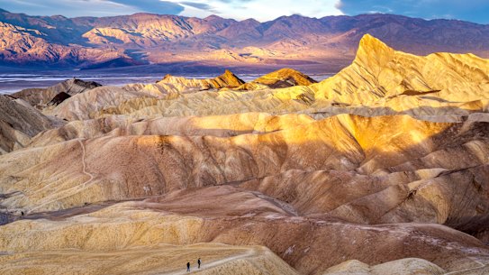 Hikers on the slopes of Zabriskie Point at sunrise.