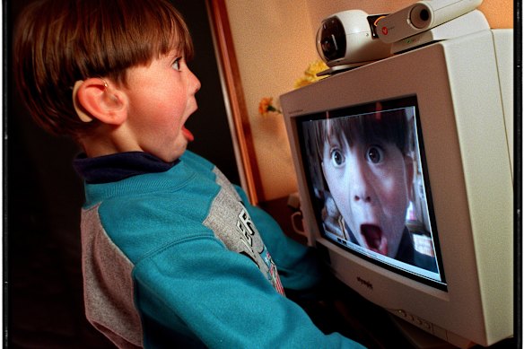 A boy looking at image of himself on the computer screen.