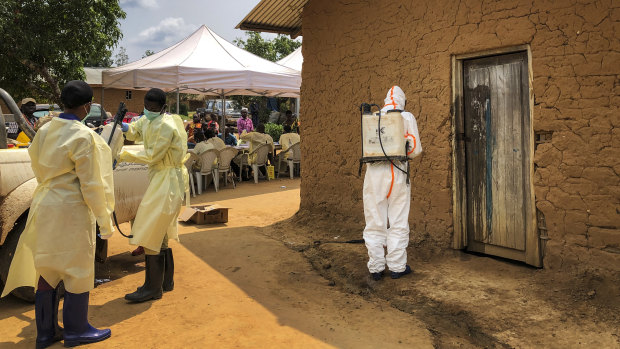 A worker from the World Health Organisation decontaminates the doorway of a house on a plot where two cases of Ebola were found in the village of Mabalako, eastern DRC.