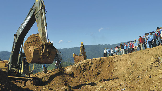 Excavators dig through soil to search for bodies of miners as workers and rescue members gather in Hpakant, Kachin State, Myanmar, in 2015 when landslides killed at least 116.