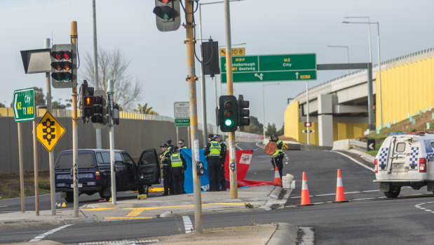 Police at the Mickleham Road pedestrian lights near the entry ramp to the Tullamarine Freeway where a woman was believed to have been crossing when she was struck and killed. 