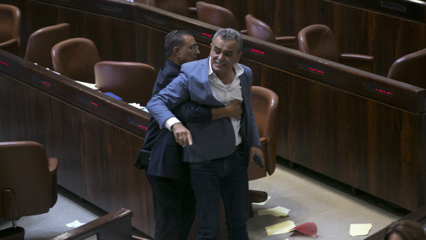 A Knesset usher removes Jamal Zahalka, an Israeli Arab member of the Knesset representing the Balad party, who was protesting against the passage of the bill.