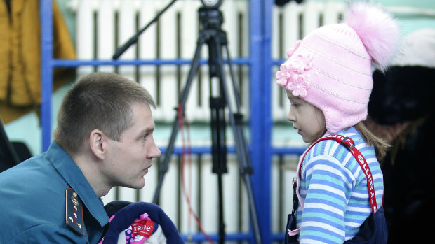 An Emergency Situations employee speaks to a girl in an evacuation centre near a collapsed section of the apartment building in Magnitogorsk.