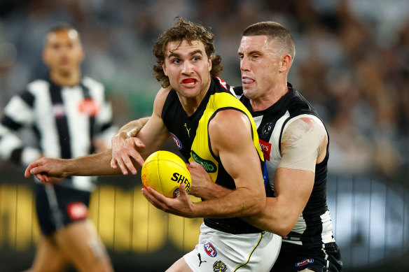 Jack Ross of the Tigers is tackled by Darcy Cameron of the Magpies.