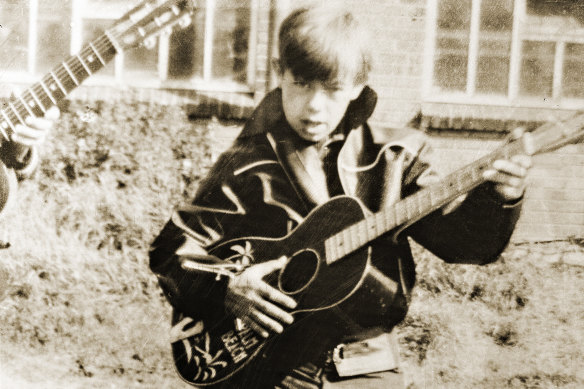 A young Bernie Taupin channels Eddie Cochran, playing a guitar with no strings.
