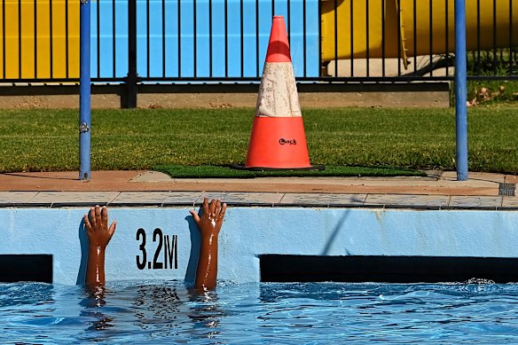 Jhamari Trapman, 9, reaches up out of the water while swimming after school at the pool in Nyngan. 