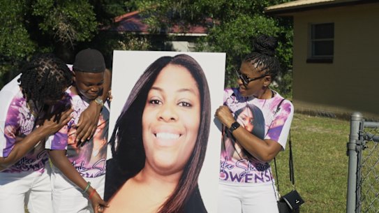 Family members hold up a photo of Ajike Owens at his memorial service.