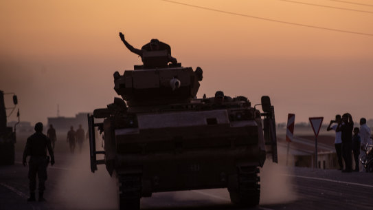 People wave as Turkish soldiers prepare to cross the border into Syria at Akcakale, Turkey.