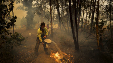 An Oakdale resident defends his home on Friday. Corporate Australia and rich listers have pledged millions of dollars to help firefighters and affected communities. 