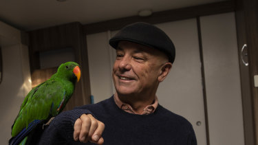 Geoff Belmore and parrot George sit in his temporary caravan.