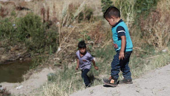 Migrant children wait for their father on the Mexican side of the Rio Bravo before crossing the US-Mexico border between Ciudad Juarez and El Paso.
