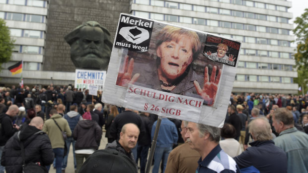A protester holds a poster with a photo of Angela Merkel reading 'Merkel must go'  in Chemnitz, eastern Germany, on Saturday.