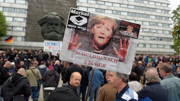 A protester holds a poster with a photo of Angela Merkel reading 'Merkel must go'  in Chemnitz, eastern Germany, on Saturday.