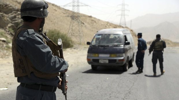 Afghan police officers search a vehicle at a checkpoint on the Ghazni highway.