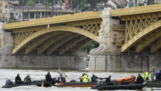 Rescuers in boats work to prepare to recover the capsized boat.