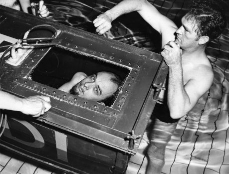 The Amazing Randi, professional escapologist peers out from the sealed coffin in which he will attempt to break his own endurance record of staying two hours under water, at the West Ham Municipal Baths in London, 1958.  