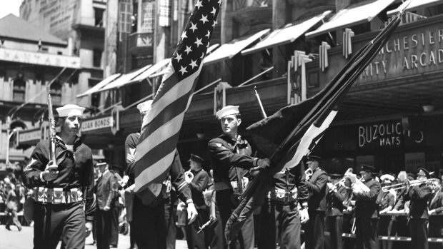 U.S. Navy standard-bearers with Stars & Stripes and Navy flag lead American servicemen on a march down Flinders Street, Melbourne.