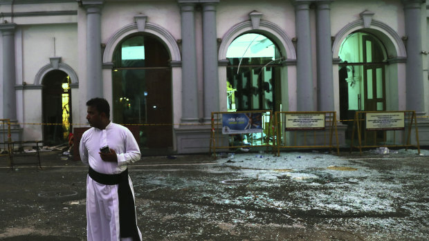 A Sri Lankan catholic priest stands near broken glass in front St. Anthony's Church in Colombo.