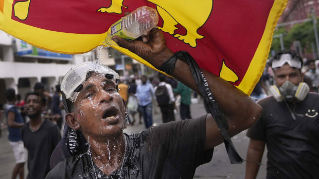A protester washes his eyes to avoid tear gas effect during a protest in Colombo this month.