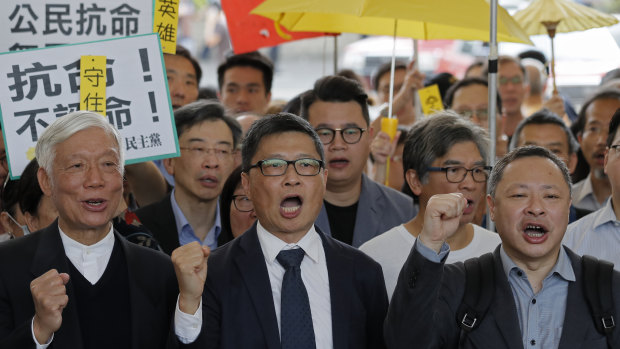 Occupy Central leaders, from right, Benny Tai, Chan Kin Man and Chu Yiu Ming shout slogans before entering a court in Hong Kong on Tuesday.