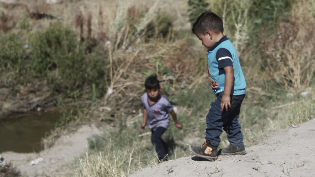 Migrant children wait for their father on the Mexican side of the Rio Bravo before crossing the US-Mexico border between Ciudad Juarez and El Paso.