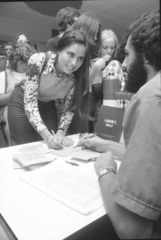 “Annette Finkel, 19, of Elwood, in her second year of Art at Monash, fills in the enrolment form, aided by Mark Plummer, one of five students who staffed the table set up in the Union building.”