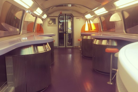 The spacious canteen carriage where dining counters face towards large, panoramic windows.